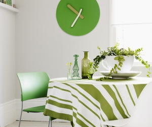 jídelní kout zařízený v zelené barvě s hodinami a jídelním stolem se zeleným ubrusem