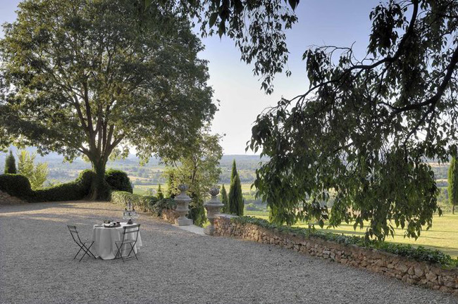 jednoduché zahradní židle a prostřený stůl s výhledem na zelené údolí