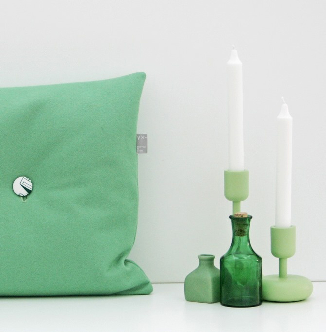 zelený polštář s knoflíkem a zelené svícny na svíčky