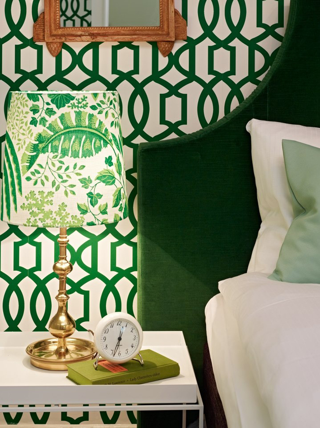 noční stolek s budíkem a se stojící lampičkou se stínidlem se zeleným vzorem