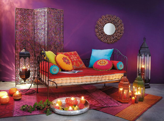 paraván a divan s barevnými polštáři a svíčkami v místnosti s fialovou zdí